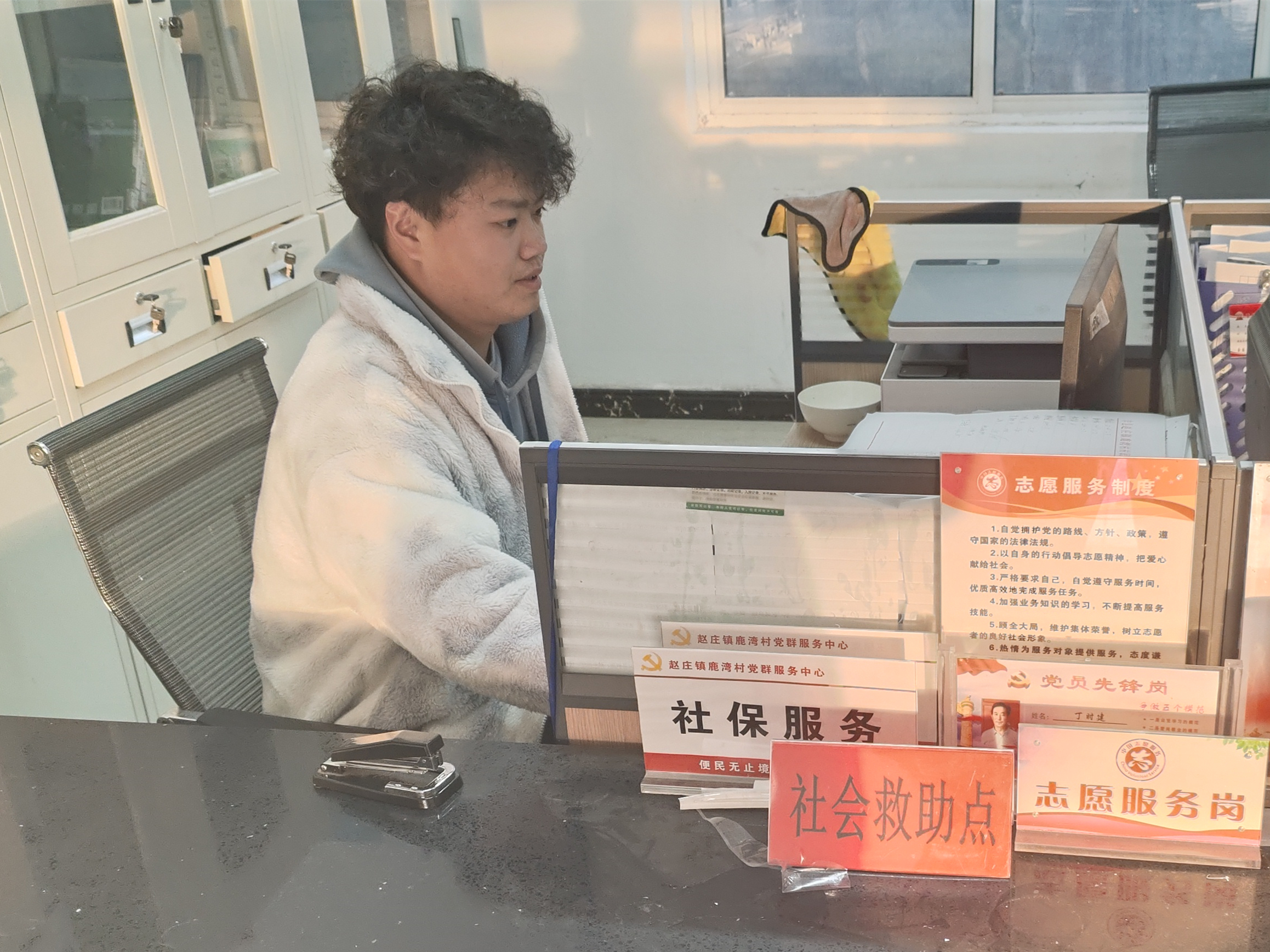 图为学生陆宇浩在江苏省徐州市丰县赵庄镇鹿湾村委会进行寒假社会实践，他主要负责整理村民信息并录入电脑系统，处理和撰写一些通知文件。